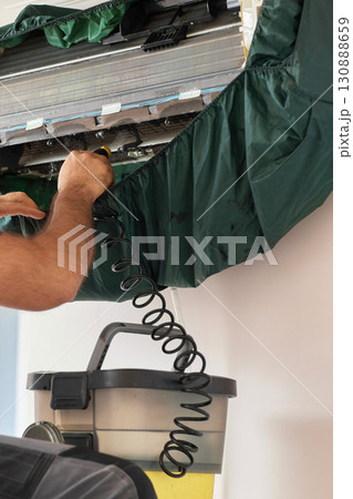 male hand of worker from the cleaning service cleans the air conditioner by spraying water, close-up male hand of worker from the cleaning service cleans the air conditioner by spraying water, close-up 130888659