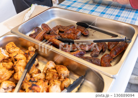 Grilled sausages and kebabs on serving trays at a Swedish table buffet. 130889094