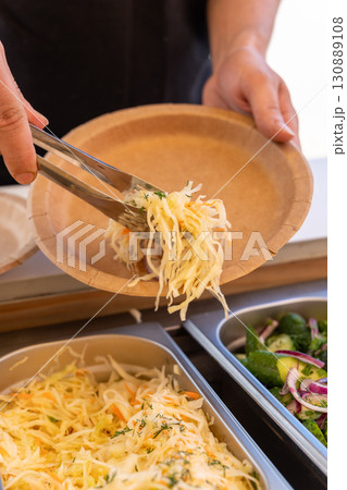 A visitor serves sauerkraut salad from a buffet 130889108