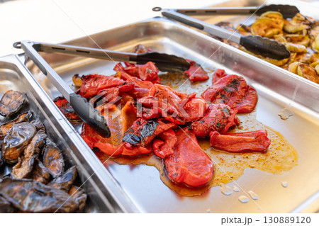 Baked bell peppers on a charcoal grill, served on a platter for a buffet. 130889120