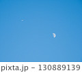 青空に浮かぶ半月と飛行機 130889139