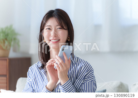 スマホを使う笑顔の若い女性 130890119