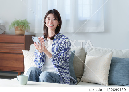 スマホを使う笑顔の若い女性 130890120