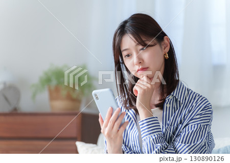スマホを持って考える若い女性 130890126