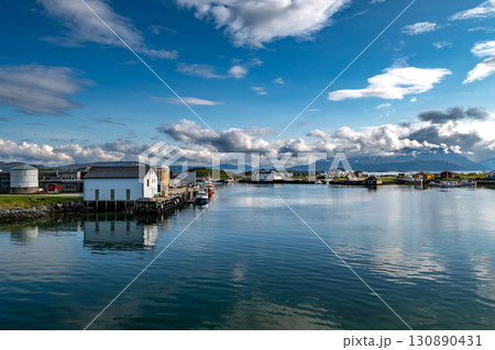 Harbor With Small Ships Of Sommaroy In Front Of Snowy Mountains In Norway Harbor With Small Ships Of Sommaroy In Front Of Snowy Mountains In Norway 130890431