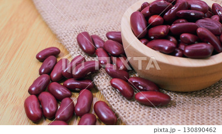 Close-up of red kidney beans in a wooden bowl with beans scattered on burlap sack and wooden background. Perfect for concepts of organic farming 130890462