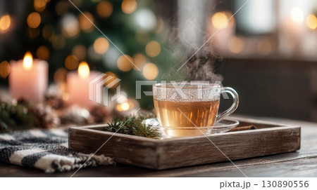 Cozy Glass of Hot Tea on Wooden Tray with Steam and Warm Ambiance 130890556