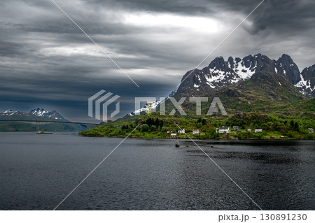Coastal Landscape With Small Village And Snowy Mountains Near Stokmarknes At The Lofoten In Norway Coastal Landscape With Small Village And Snowy Mountains Near Stokmarknes At The Lofoten In Norway 130891230