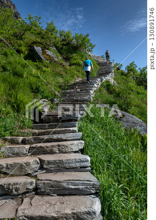 Woman Hiking On Steep Sherpy Stairs On Reinebringen Trail On Lofoten Islands In Norway Woman Hiking On Steep Sherpy Stairs On Reinebringen Trail On Lofoten Islands In Norway 130891746
