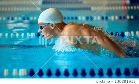 Swimmer performing butterfly stroke emerging powerfully from water Swimmer performing butterfly stroke emerging powerfully from water 130891915