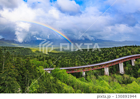 青空と雨雲の狭間に輝く虹と三国峠の森 130891944