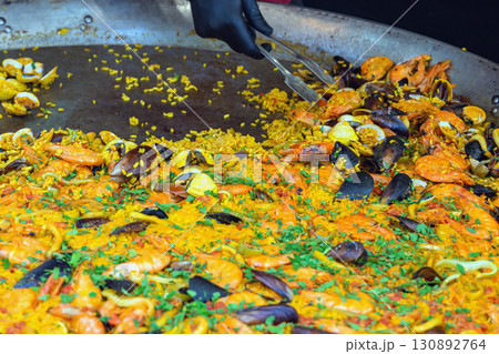 Traditional Spanish paella with rice, shrimp, mussels, and clams cooked in a large pan. Concept of seafood paella, Mediterranean cuisine, festive food tradition Traditional Spanish paella with rice, shrimp, mussels, and clams cooked in a large pan. Concept of seafood paella, Mediterranean cuisine, festive food tradition 130892764
