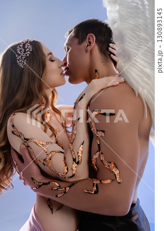 Romantic embrace between a couple with artistic body paint and angelic wings 130893145