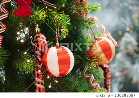 Festive shiny Christmas Tree with red and white striped baubles. Xmas holiday festivities and celebration. Close up. 130895087