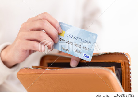 財布からクレジットカードを取り出すカジュアルのミドル女性 130895785