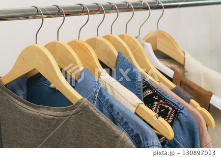 Upcycled denim fashion displayed on wooden hangers in a modern boutique. Eco thrifting lifestyle. 130897013