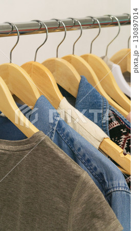 Upcycled fashion showcasing second hand denim on wooden hangers in a stylish display 130897014