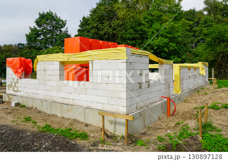 New house construction with aerated concrete blocks and protective covers on building site 130897128