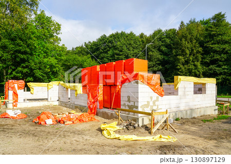 Construction site with aerated concrete block walls and protective covers during building process 130897129