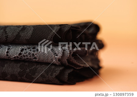 Stack of black lace fabrics, shallow focus Stack of black lace fabrics, shallow focus 130897359