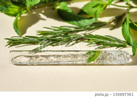 A test tube with the texture of serum or other cosmetics with mint and herbs. A test tube with the texture of serum or other cosmetics with mint and herbs. 130897361
