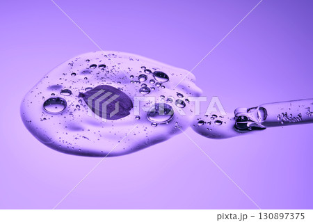 A pipette with cosmetic serum and lilac petals. A pipette with cosmetic serum and lilac petals. 130897375