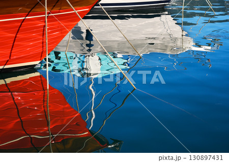 Reflection of moored yachts in the clear blue water of the sea port Reflection of moored yachts in the clear blue water of the sea port 130897431