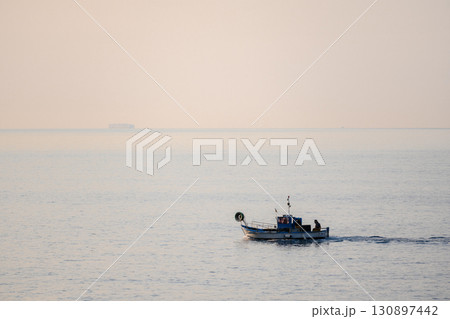 Small lonely fishing boat with lonely fisherman 130897442