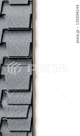Gray textured roof shingles form a vertical pattern on the left side. The shingles have a layered design, creating shadow and depth. The right side is light in color Gray textured roof shingles form a vertical pattern on the left side. The shingles have a layered design, creating shadow and depth. The right side is light in color 130899244