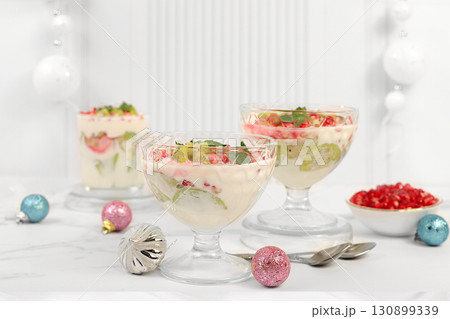 Kiwi and pomegranate parfait on a bright festive table, an idea for decorating food and decorating New Year's dishes. Banner for the screen , template for creativity. Christmas and New Year's dishes. 130899339