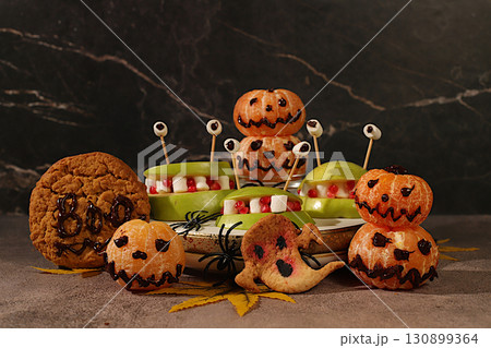Horrible monsters made of apples, tangerines and pumpkin ghosts on an old concrete background, cafe advertising and menu, restaurant business card, Halloween food concept, holiday meal idea Horrible monsters made of apples, tangerines and pumpkin ghosts on an old concrete background, cafe advertising and menu, restaurant business card, Halloween food concept, holiday meal idea 130899364