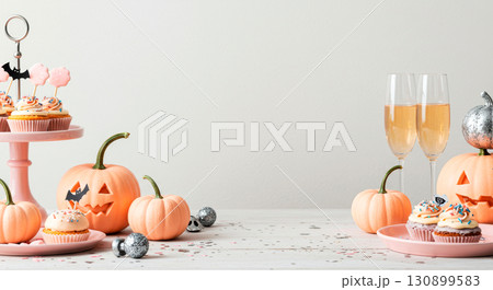 Pastel Halloween party table with cupcakes, festive pumpkins, and champagne glasses 130899583
