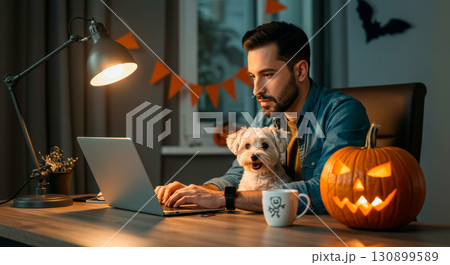 Focused professional working from a decorated home office with his dog for Halloween 130899589