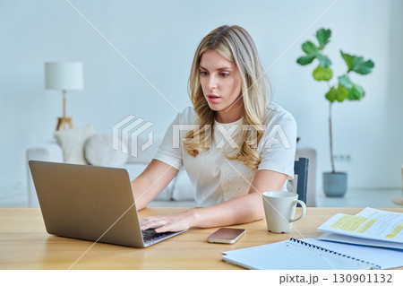 Young woman university student sitting at desk with laptop, typing writing studying Young woman university student sitting at desk with laptop, typing writing studying 130901132