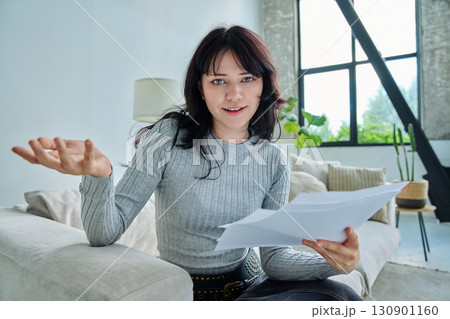 Web cam view of young woman with papers, online meeting, video call 130901160