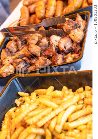 Sizzling street food feast: grilled sausages, shashlik, and golden french fries 130901233