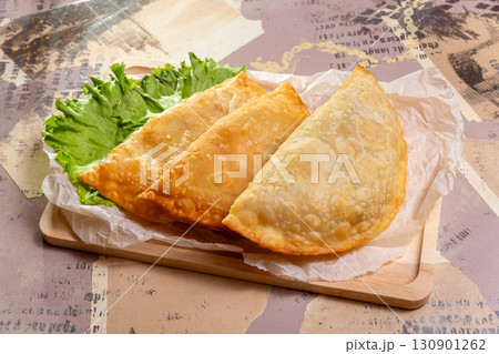 Three large fried chebureki on a wooden board 130901262