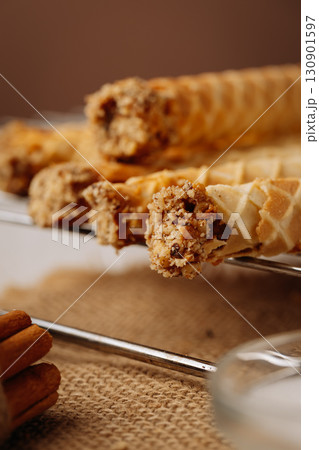 Close up of crispy wafer rolls with nut filling on rustic burlap and metal rack Close up of crispy wafer rolls with nut filling on rustic burlap and metal rack 130901597