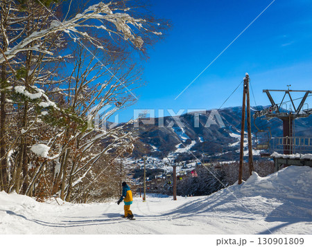 青空が美しい冬のゲレンデとスノーボーダーの後ろ姿 (長野県、山ノ内町、X-JAM高井富士) 130901809