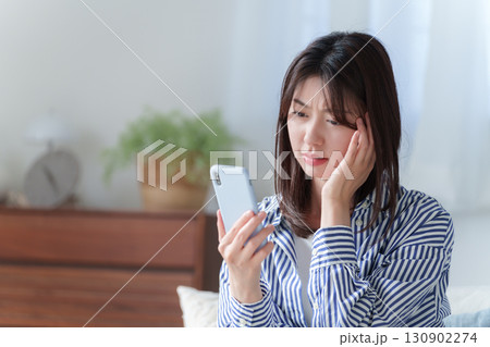 スマホを持って落ち込む若い女性 130902274