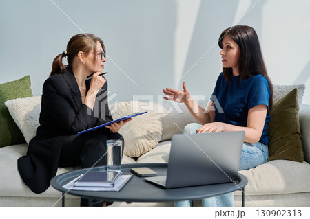 Female patient talking to psychotherapist psychologist, sitting together in office 130902313