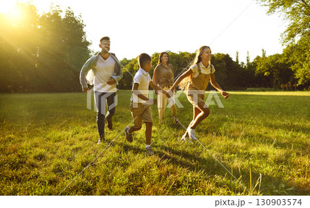 Cheerful young family with two children having fun and playing in summer park. Cheerful young family with two children having fun and playing in summer park. 130903574