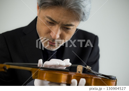 バイオリンをメンテナンスするシニア男性  130904527