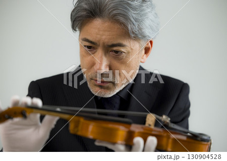 バイオリンをメンテナンスするシニア男性  130904528