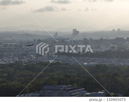 （鳥瞰）　夕暮れの街上空から調布飛行場に向けて着陸する小型旅客機 130905073