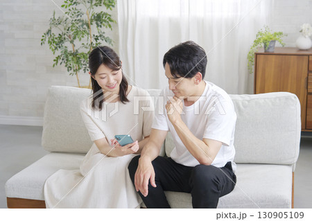 リビングでスマホを使うカップル リビングでスマホを使うカップル 130905109