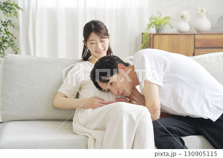 妊娠中の妻のお腹に耳を当てる夫 130905115