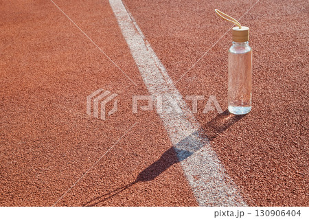 Reusable glass water bottle at stadium on sunny day close-up 130906404