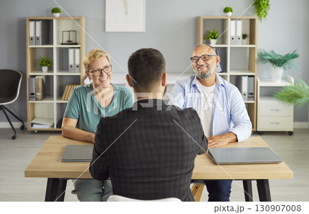 Senior couple meets friendly financial advisor to review documents in office Senior couple meets friendly financial advisor to review documents in office 130907008
