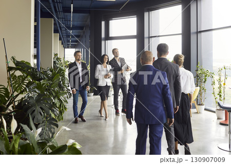 Business people walking down office hall towards each other, employees greeting 130907009